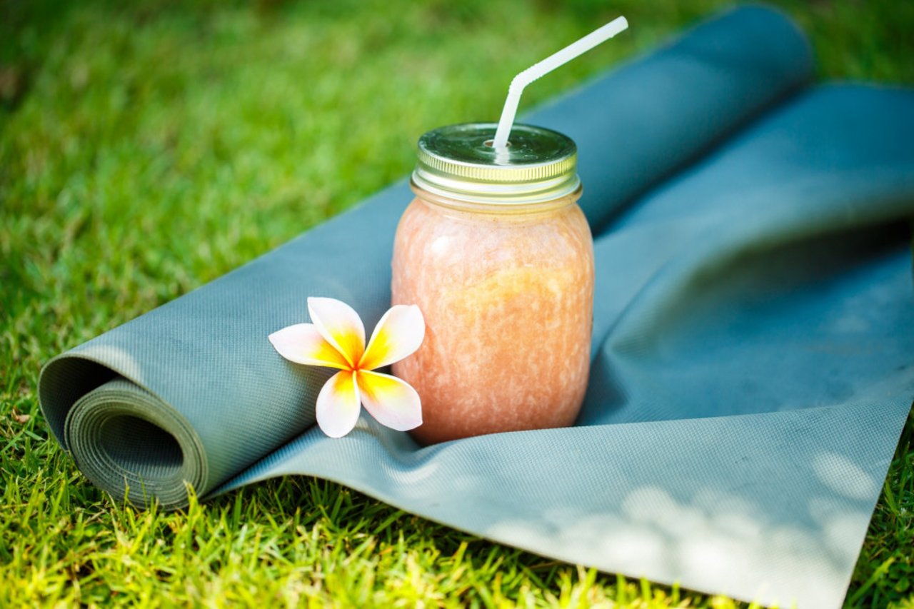 Plant-based Smoothies and yoga mat on the grass