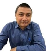 Wildlife Research Manager Shubhobroto Ghosh looks towards the camera dressed in a blue shirt and is pictured against a white background